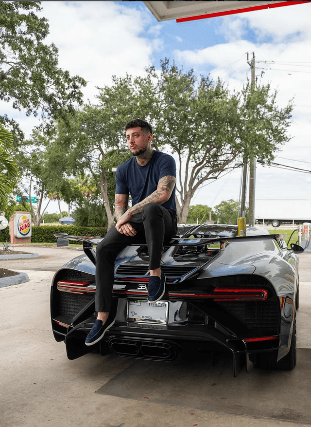 Raul sitting on black supercar